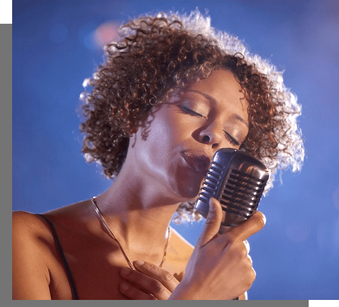 A woman with curly hair is singing into a microphone.