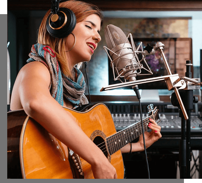 A woman with headphones on playing an acoustic guitar.