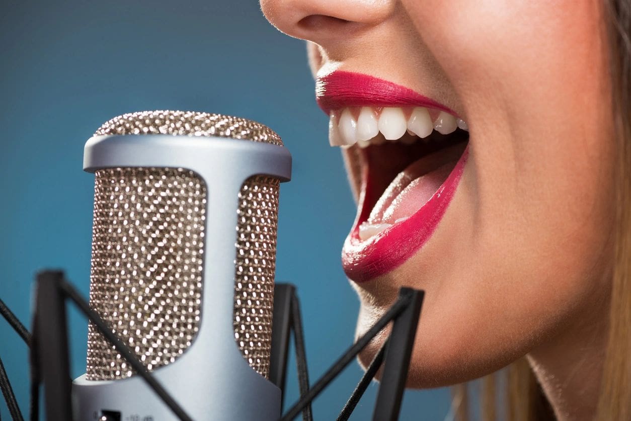A woman with red lipstick is singing into a microphone.